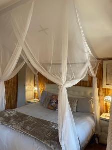 a bedroom with a canopy bed with white curtains at Iris Retreat & Island Day Spa in Hartbeespoort