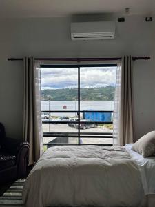 a bedroom with a bed and a large window at Hostal Umantun in Dalcahue