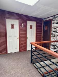 2 puertas blancas en una habitación con escalera en Hostal Umantun, en Dalcahue