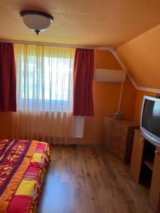 - une chambre avec un lit, une fenêtre et une télévision dans l'établissement Bükk-Szép Villa, à Bükkszék