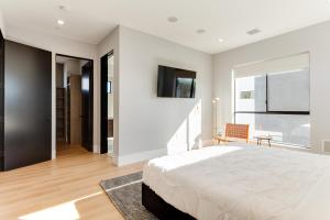 een witte slaapkamer met een bed en een televisie bij Brand New Modern 4 Bedroom House Pickfair Village in Los Angeles