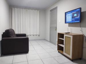 Una sala de estar con una silla y un televisor. en Casa completa - Governador Celso Ramos à 15min da praia de palmas, en Governador Celso Ramos