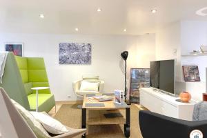 a living room with a tv and a chair at Loft de l'Artiste - Parking - Standing in Rouen