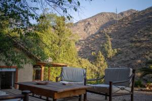 two chairs and a wooden table on a patio with mountains at Casa Camino Farellones in Santiago