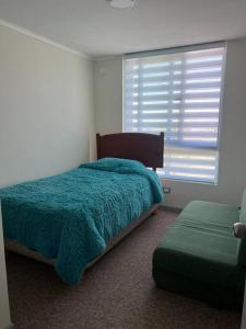 a bedroom with a blue bed and a window at Departamento Peñuelas in Coquimbo