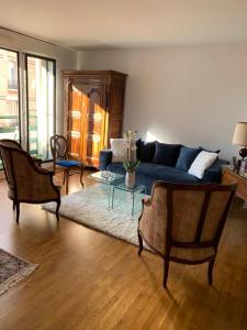 ein Wohnzimmer mit einem blauen Sofa und Stühlen in der Unterkunft PARIS 10 ' BASTILLE (CHARENTON LE PONT) in Charenton-le-Pont