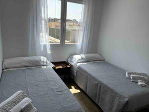 two beds in a room with a window at Apartamento Virgen del Mar in Almería