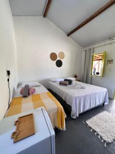 a bedroom with two beds and a table at Vila Cajuzinho in Caraíva