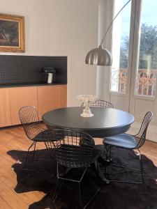 une table à manger noire avec des chaises et une lampe dans l'établissement Suite haussmannienne en Sologne, à Vierzon