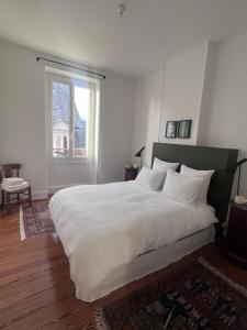 - une chambre avec un grand lit blanc et une fenêtre dans l'établissement Suite haussmannienne en Sologne, à Vierzon