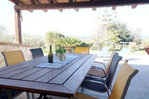 een houten tafel met stoelen en een fles wijn bij Asinara Appartment in Sorso