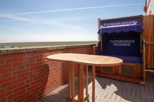 einen Holztisch auf einem Balkon mit Ziegelwand in der Unterkunft Ankerplatz über dem Hafen-Pub in Pellworm