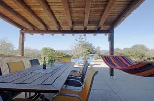 een houten tafel met stoelen en een hangmat op een patio bij Asinara Appartment in Sorso