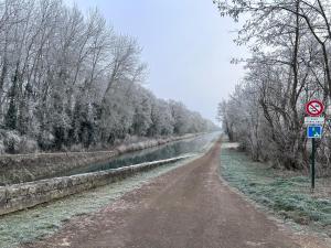 a dirt road next to a river with a sign at La petite maison in Brienon-sur-Armançon