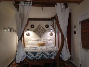 a bedroom with a canopy bed with white sheets at Aloha Crater Lodge in Volcano
