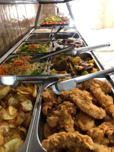 a buffet filled with different types of food in trays at Hotel Pousada Lega's in Aparecida