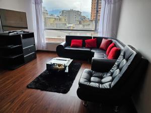 a living room with a black couch and red pillows at 2 habitaciones en centro de pasto parqueadero y baño privado in Pasto
