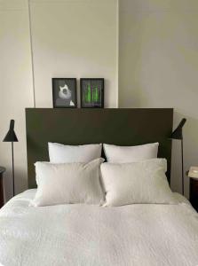 - une chambre avec un lit blanc et deux photos au-dessus dans l'établissement Suite haussmannienne en Sologne, à Vierzon