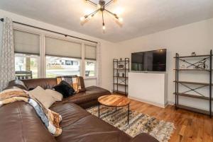a living room with a brown leather couch and a table at Pet Friendly House with Bike Trail Access and Huge Fenced Yard in Greenville