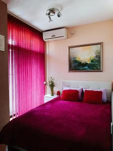 a bedroom with pink curtains and a large bed at M Central Park in Niš