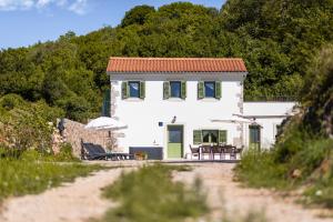 a white house with green shutters on a beach at Hidden House Porta in Krk