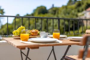 een houten tafel met eten en glazen sinaasappelsap bij Hidden House Porta in Krk