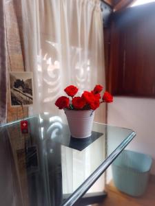 a vase of red roses sitting on a glass table at Villa Monserrate Bed and Breakfast in Bogotá