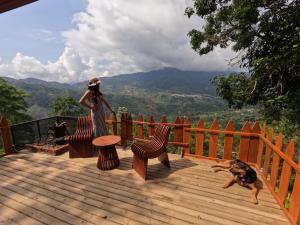 una mujer parada en una terraza de madera con un perro en Villa Colombia en Vianí