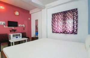 una camera con un letto bianco e una parete rossa di Hotel Nilay And Banquet (Vivaah Palace) a Kahalgaon