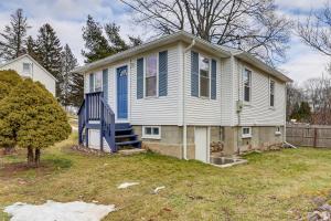 a white house with a blue door on a yard at Wolcott Home with Deck Near Connecticut Attractions in Wolcott