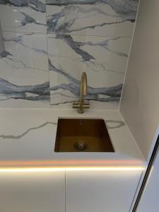 a sink in a bathroom with a marble wall at 2bedroom apartment/steam room in Carnoustie