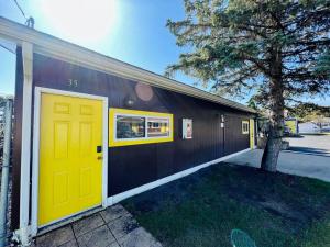 a building with a yellow door and a tree at Studio at Snooze in Wisconsin Rapids