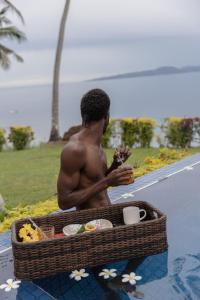 a shirtless man sitting next to a basket of food at Lomani in Matei