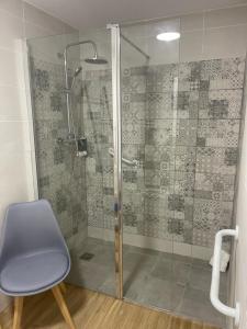 y baño con ducha con puerta de cristal y silla. en HOTEL apartamentos SEVEN ROOMS, en Punta Umbría