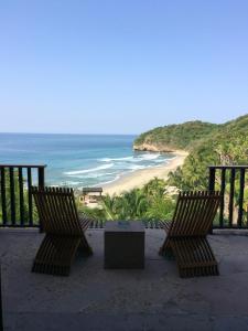 two chairs and a table on a balcony overlooking a beach at Imanta Resorts Punta de Mita in Punta Mita