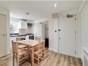 Il comprend une cuisine et une salle à manger avec une table et des chaises en bois. dans l'établissement flat 7 mornington crescent, à Londres
