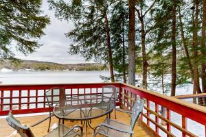 a table and chairs on a deck overlooking a lake at Hermit Lake Retreat in Sanbornton