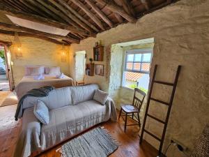 Casa Anjos Holiday Cottages في Areias: غرفة نوم مع أريكة وسرير ونافذة