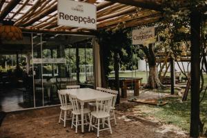 una mesa blanca y sillas bajo una pérgola en Pousada Recanto das Cerejeiras en Río Grande