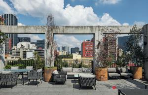 un patio all'ultimo piano con divano, tavoli e sedie di Casa Londres by Kukun a Città del Messico