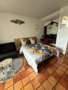1 dormitorio con cama, silla y espejo en Studio MESANGE TARTANE en La Trinité