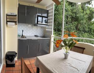 a kitchen with a table with a vase of flowers on a balcony at Studio MESANGE TARTANE in La Trinité
