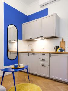 una cucina con armadi bianchi e parete blu di MiodLove Apartment a Cracovia