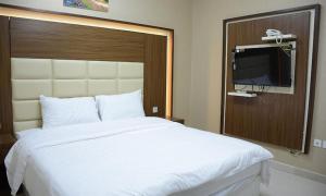 a bedroom with a large white bed with a flat screen tv at تراس للأجنحة الفندقية in Dammam