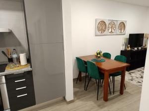 a kitchen and dining room with a table and green chairs at Garden House Fundão - Apartamento 201 com 2 quartos com vista jardim in Fundão