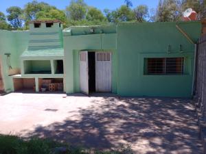 una casa verde con una puerta en el patio en POSADA CUATRO HERMANOS en Tinogasta