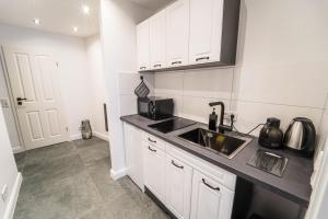 a white kitchen with a sink and a microwave at Uferzauber, Wohnung an der Schlachte, Innenstadt, Bremen in Bremen