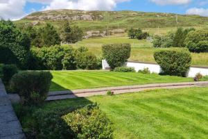 a lawn with trees and a hill in the background at Hebridean Country House in Lochs