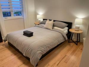 - une chambre avec un lit, 2 tables et 2 lampes dans l'établissement Le Citadin - Maison neuve moderne & ensoleillée, à Québec