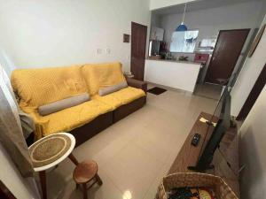 a living room with a yellow couch and a kitchen at Sonho de Itaúna in Saquarema